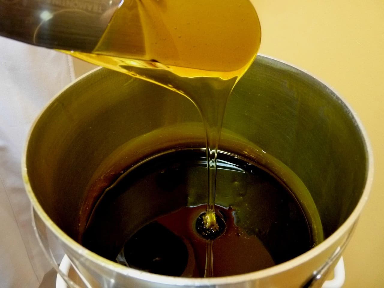 Warm honey-coloured wax being poured into a pot