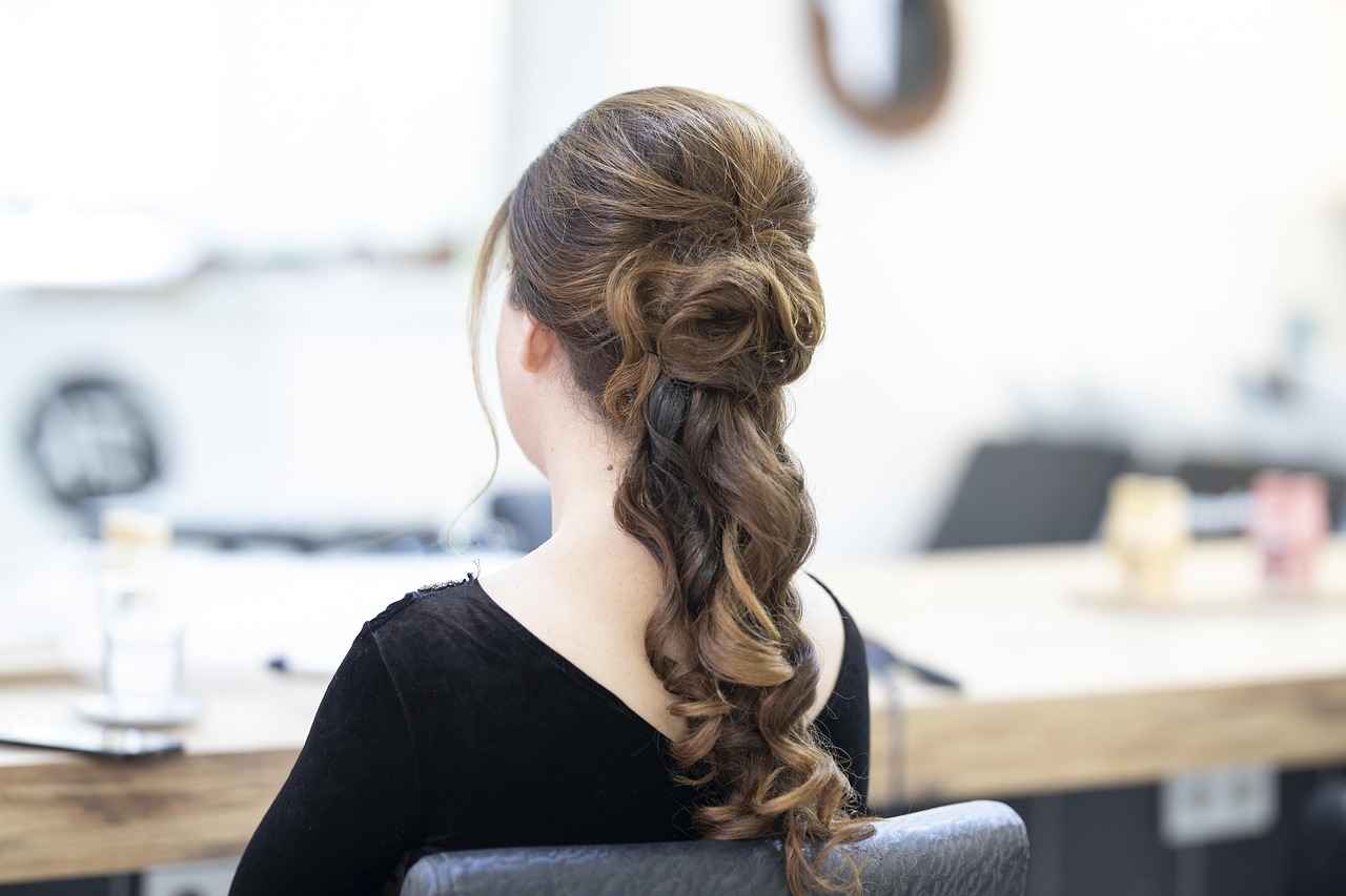 A styled updo with loose curls, seen from behind in a salon